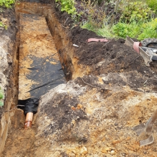 Udgravning til nedsivningsanlæg med kloakrør og klargøring i haven