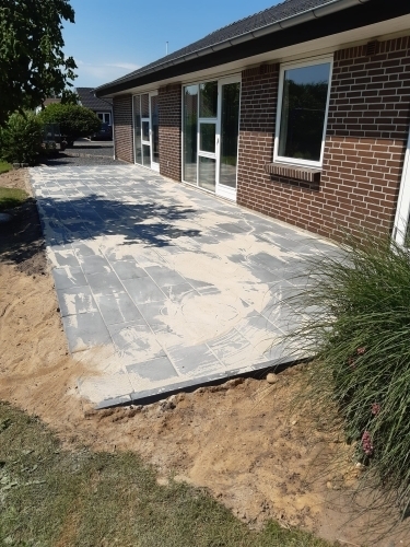 Ny fliselagt terrasse med betonfliser ved murstenshus