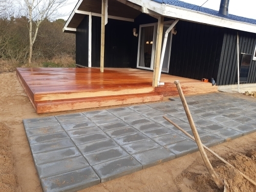 Ny flisebelægning foran træterrasse ved sort træhus