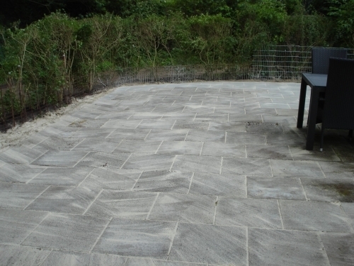Ny terrasse i haven med grå betonfliser lagt i mønster