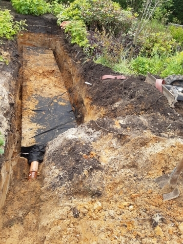 Udgravning til nedsivningsanlæg med kloakrør og klargøring i haven